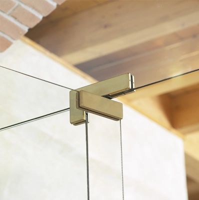 Herraje dorado sujetando un cristal junto a una viga de madera